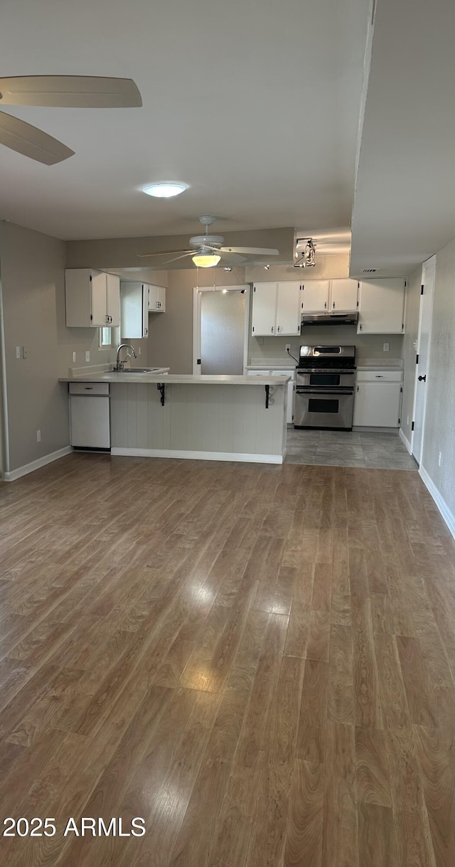 kitchen with dishwashing machine, wood finished floors, a ceiling fan, white cabinets, and double oven range