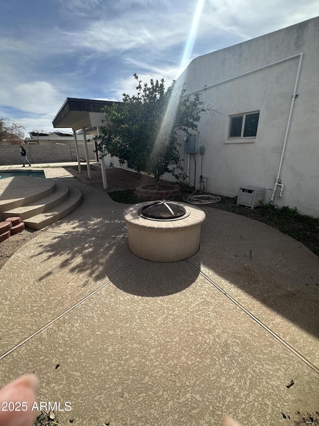 view of patio / terrace with an outdoor fire pit, a swimming pool, and fence