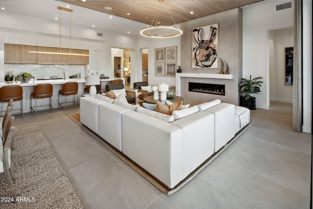 living room with a tiled fireplace, an inviting chandelier, and wood ceiling