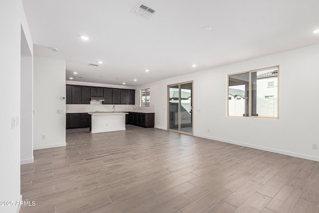 unfurnished living room featuring plenty of natural light, sink, and light hardwood / wood-style flooring