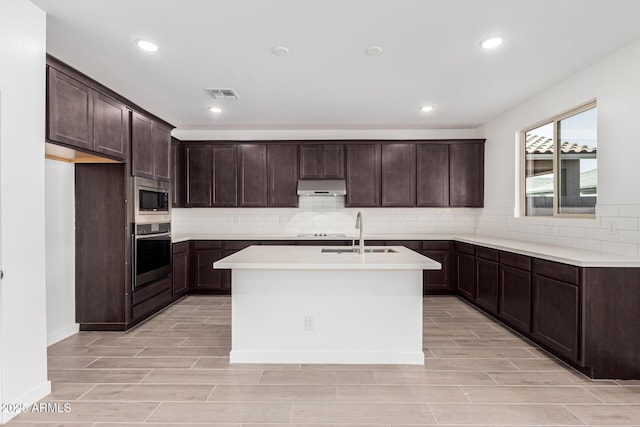 kitchen featuring an island with sink, light wood-type flooring, sink, and stainless steel appliances