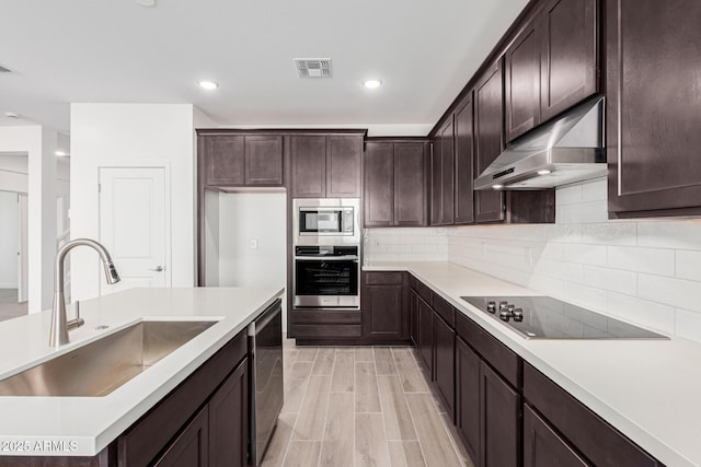 kitchen with appliances with stainless steel finishes, sink, dark brown cabinets, and backsplash