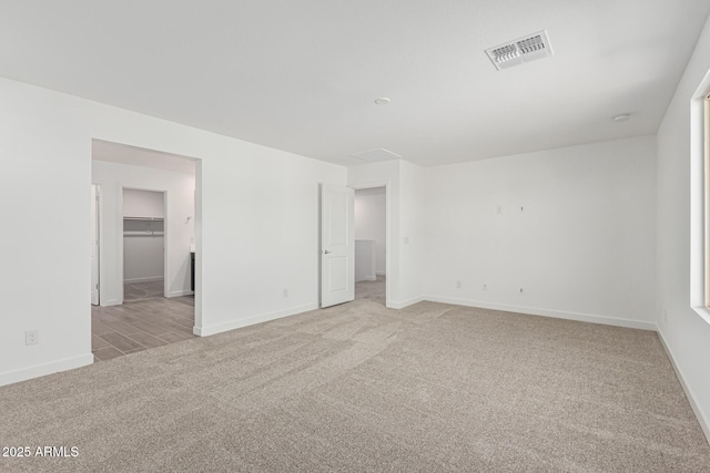 unfurnished bedroom featuring a walk in closet and light colored carpet