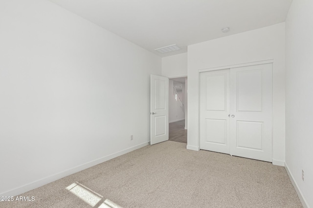 unfurnished bedroom with a closet and light carpet