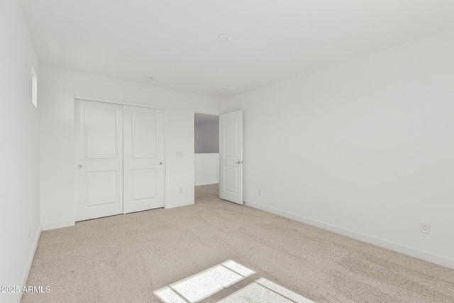 unfurnished bedroom with light carpet and a closet