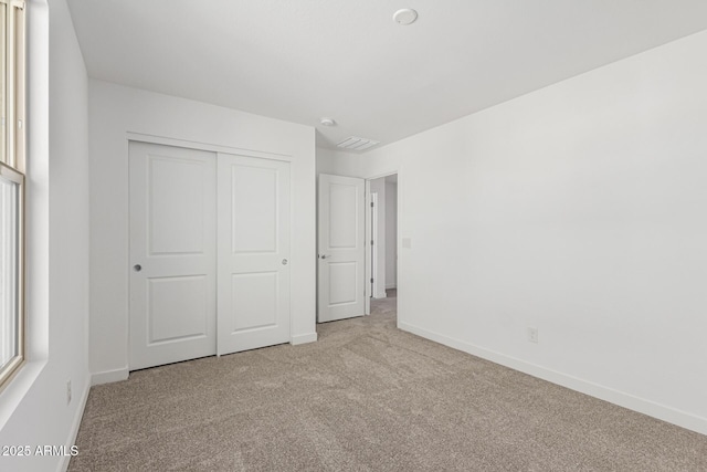 unfurnished bedroom with light carpet and a closet