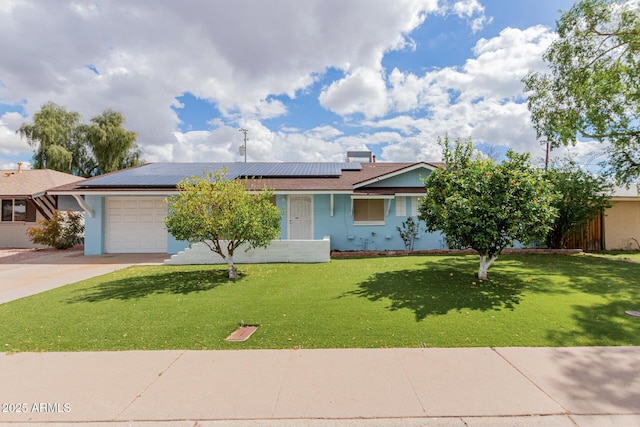 ranch-style home with driveway, an attached garage, a front lawn, and roof mounted solar panels