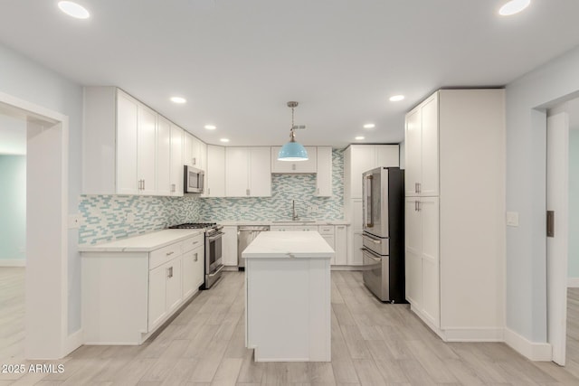 kitchen featuring a sink, light countertops, appliances with stainless steel finishes, white cabinetry, and backsplash