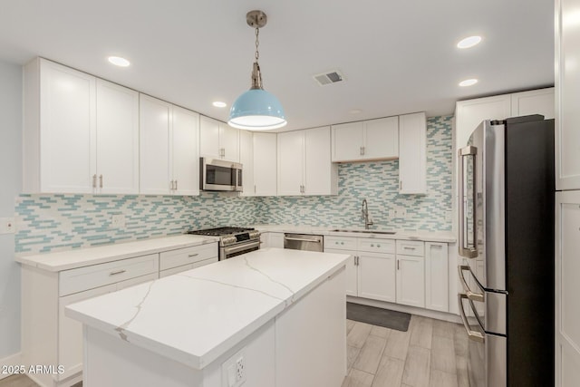 kitchen with visible vents, a sink, a kitchen island, appliances with stainless steel finishes, and decorative backsplash