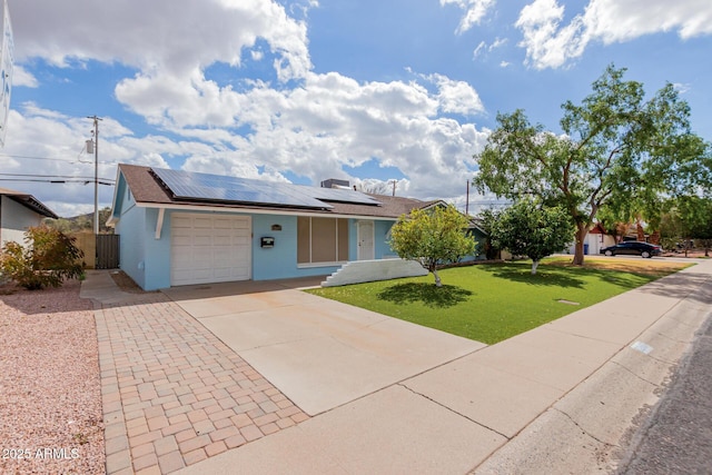 ranch-style house featuring driveway, roof mounted solar panels, fence, a front yard, and a garage