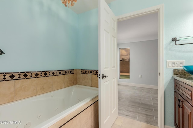 bathroom with vanity, a tub with jets, and baseboards