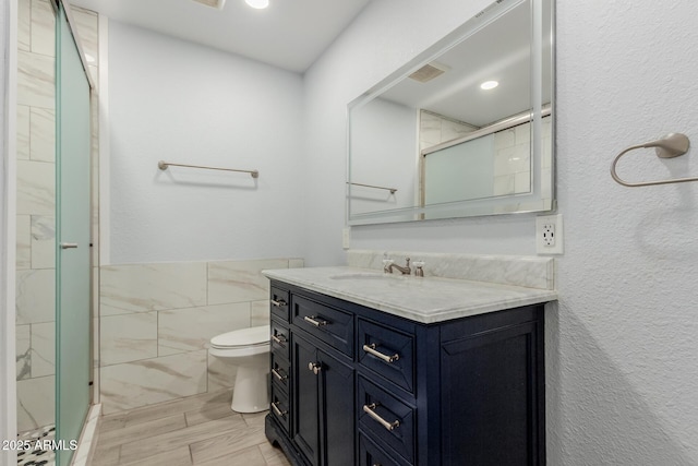 full bathroom featuring visible vents, toilet, a stall shower, tile walls, and vanity