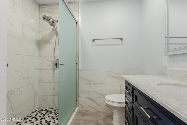 full bath with toilet, tile walls, a stall shower, and vanity