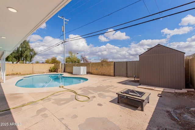 view of swimming pool with a storage unit, a patio, a fenced backyard, and an outdoor fire pit