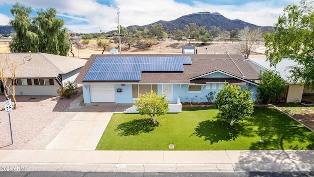 ranch-style home featuring solar panels, an attached garage, a front yard, driveway, and a mountain view