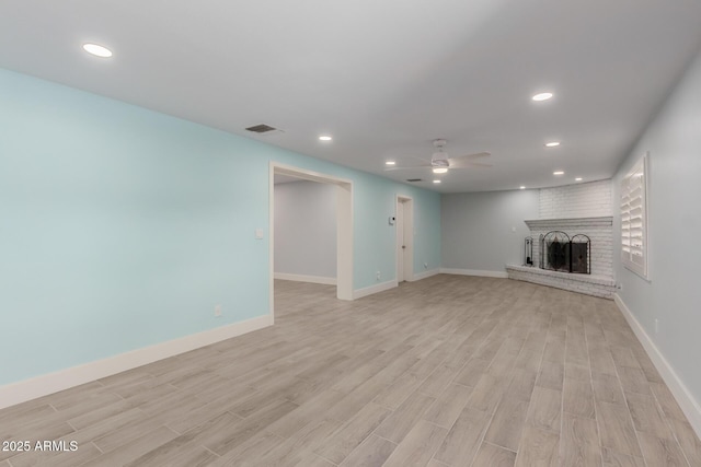 unfurnished living room featuring visible vents, a brick fireplace, ceiling fan, and light wood finished floors