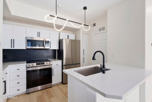 kitchen with white cabinetry, decorative light fixtures, stainless steel appliances, kitchen peninsula, and sink