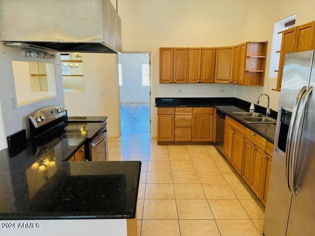 kitchen featuring light tile patterned floors, premium range hood, appliances with stainless steel finishes, kitchen peninsula, and sink