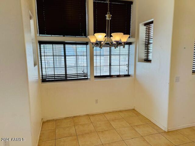 spare room with light tile patterned floors and a chandelier