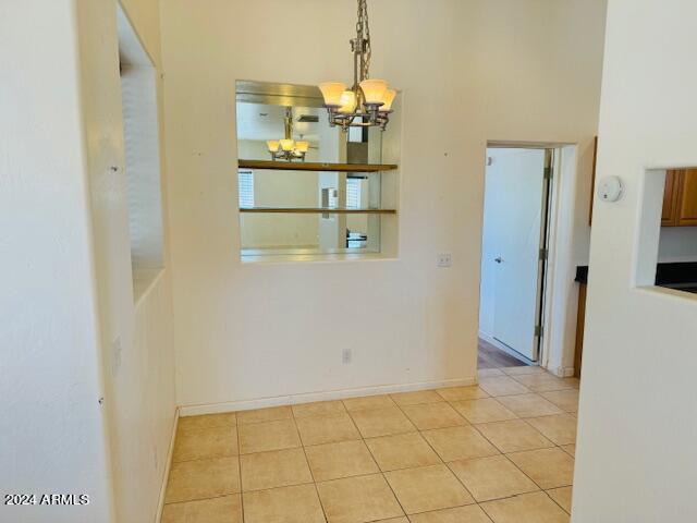 tiled empty room featuring a chandelier