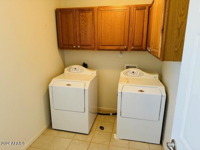 laundry room with light tile patterned floors, cabinets, and washing machine and clothes dryer