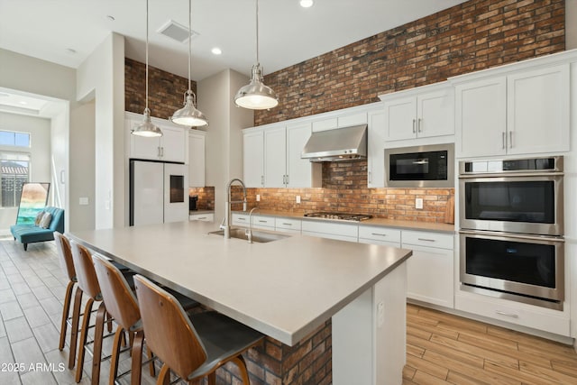 38500 N School House Rd Unit 62, Cave Creek, AZ 85331 - kitchen with visible vents, a sink, appliances with stainless steel finishes, wall chimney exhaust hood, and decorative backsplash