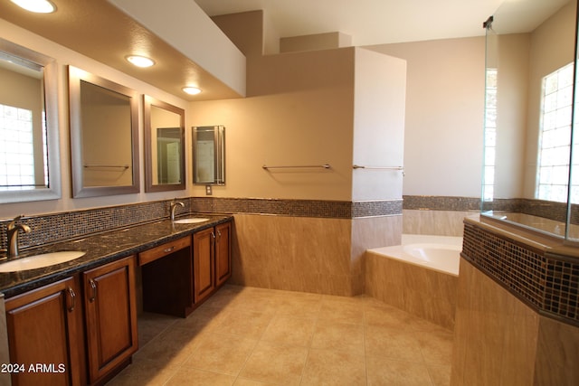 bathroom with tile patterned flooring, vanity, tile walls, and tiled tub