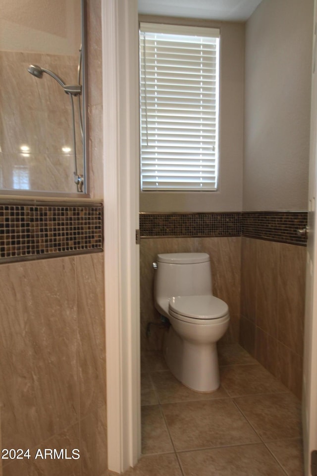 bathroom with tile patterned floors, toilet, and tile walls