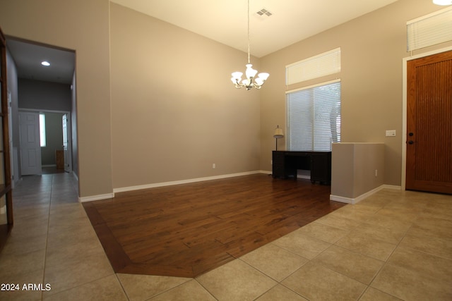 spare room featuring tile patterned flooring and a notable chandelier