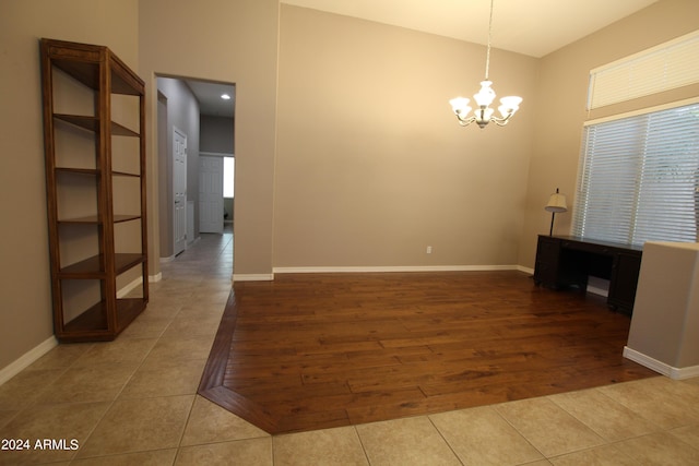 empty room with tile patterned flooring and an inviting chandelier