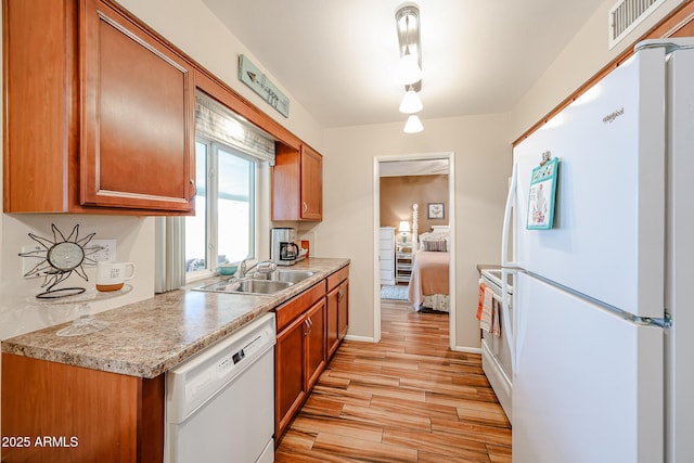 kitchen featuring white appliances, sink, and light hardwood / wood-style floors