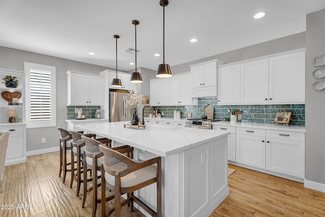 1335 W Via Del Oro, San Tan Valley, AZ 85140 - kitchen featuring appliances with stainless steel finishes, white cabinetry, a center island with sink, backsplash, and a kitchen breakfast bar