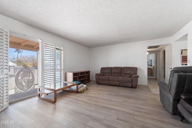 living room with light wood-style flooring, visible vents, and a textured ceiling