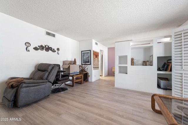 interior space featuring visible vents, a textured ceiling, and light wood finished floors