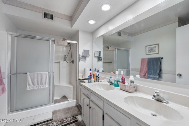 full bathroom featuring double vanity, a shower stall, visible vents, and a sink