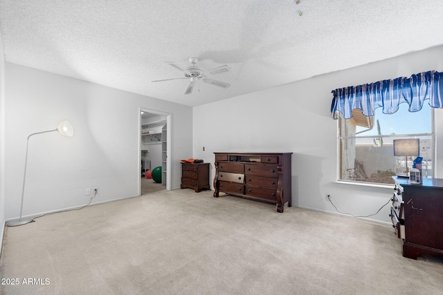 bedroom with a closet, a spacious closet, light carpet, ceiling fan, and a textured ceiling