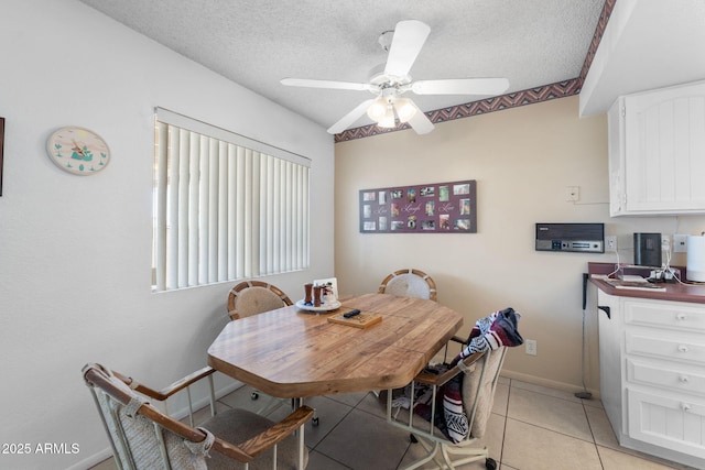 dining space with light tile patterned floors, baseboards, a ceiling fan, and a textured ceiling