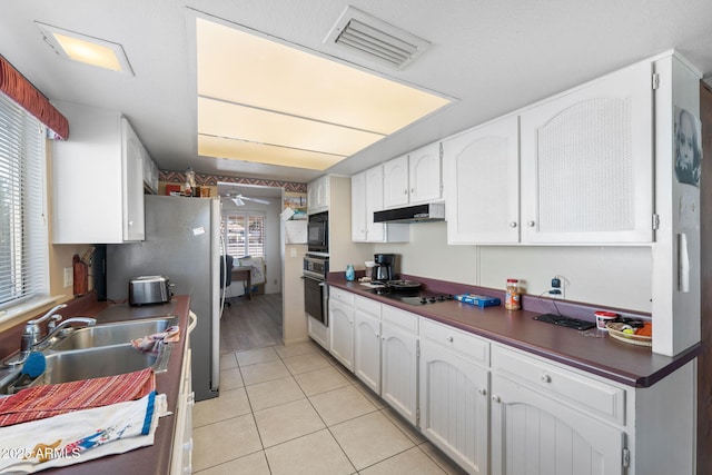 kitchen with a sink, visible vents, white cabinets, black appliances, and dark countertops