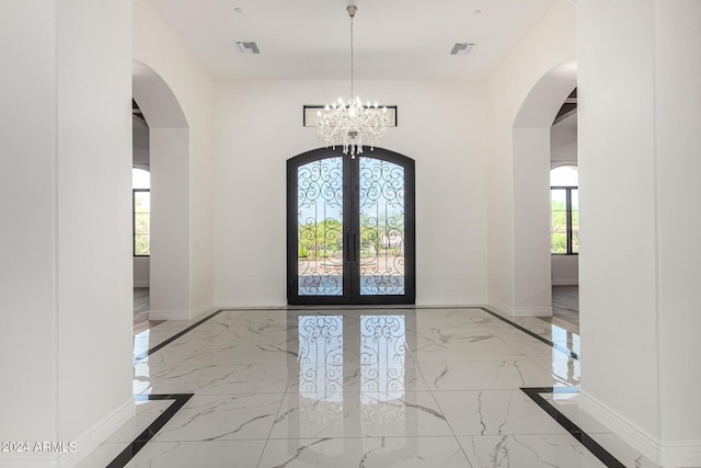 foyer with french doors, plenty of natural light, and a notable chandelier