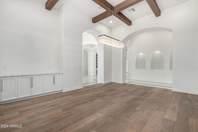 empty room with beam ceiling, light wood-type flooring, and coffered ceiling