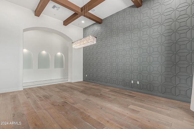 unfurnished room with beam ceiling, an inviting chandelier, light hardwood / wood-style floors, and coffered ceiling