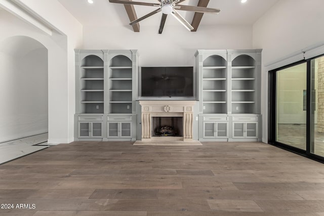 unfurnished living room with beamed ceiling, hardwood / wood-style flooring, and ceiling fan