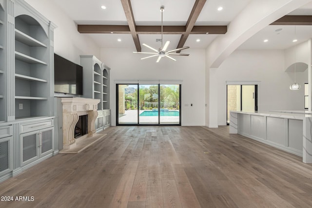 unfurnished living room featuring coffered ceiling, built in features, a premium fireplace, beamed ceiling, and wood-type flooring