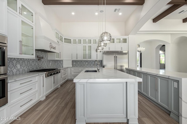 kitchen with appliances with stainless steel finishes, a center island with sink, white cabinetry, and sink