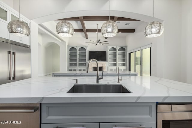 kitchen with stainless steel built in fridge, gray cabinets, light stone counters, and sink