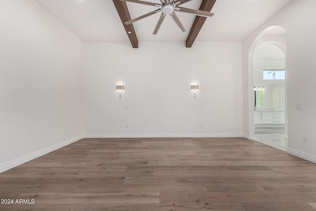 empty room with beamed ceiling, ceiling fan, and hardwood / wood-style flooring