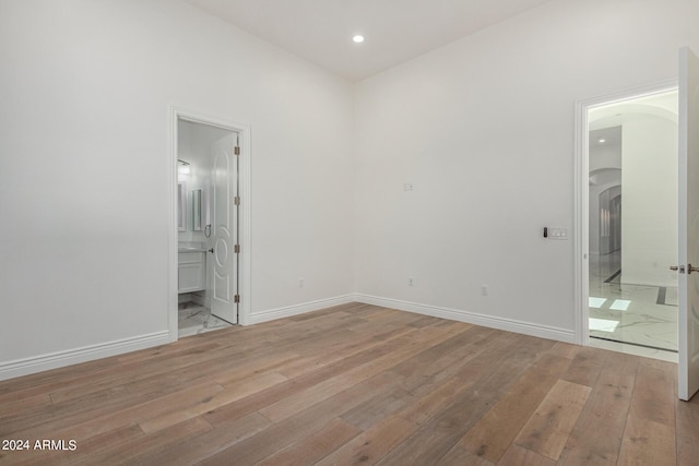 unfurnished bedroom featuring light hardwood / wood-style flooring and ensuite bath