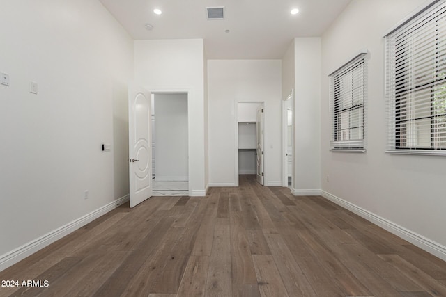 unfurnished bedroom featuring a spacious closet, a closet, and dark wood-type flooring