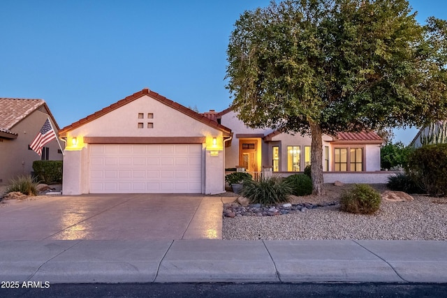 view of front of home featuring an attached garage, driveway, a tile roof, and stucco siding