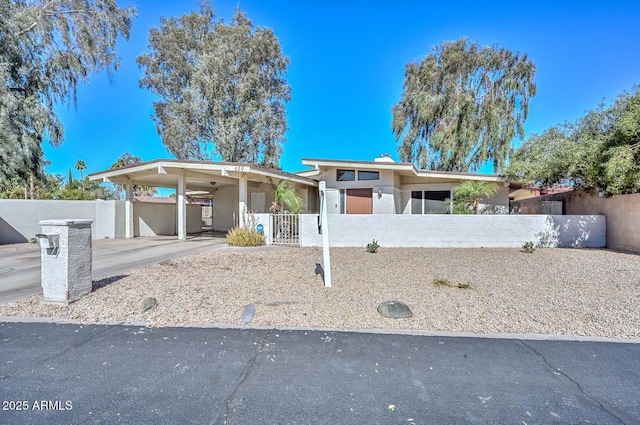 view of front of home featuring a fenced front yard, concrete driveway, a gate, and a carport